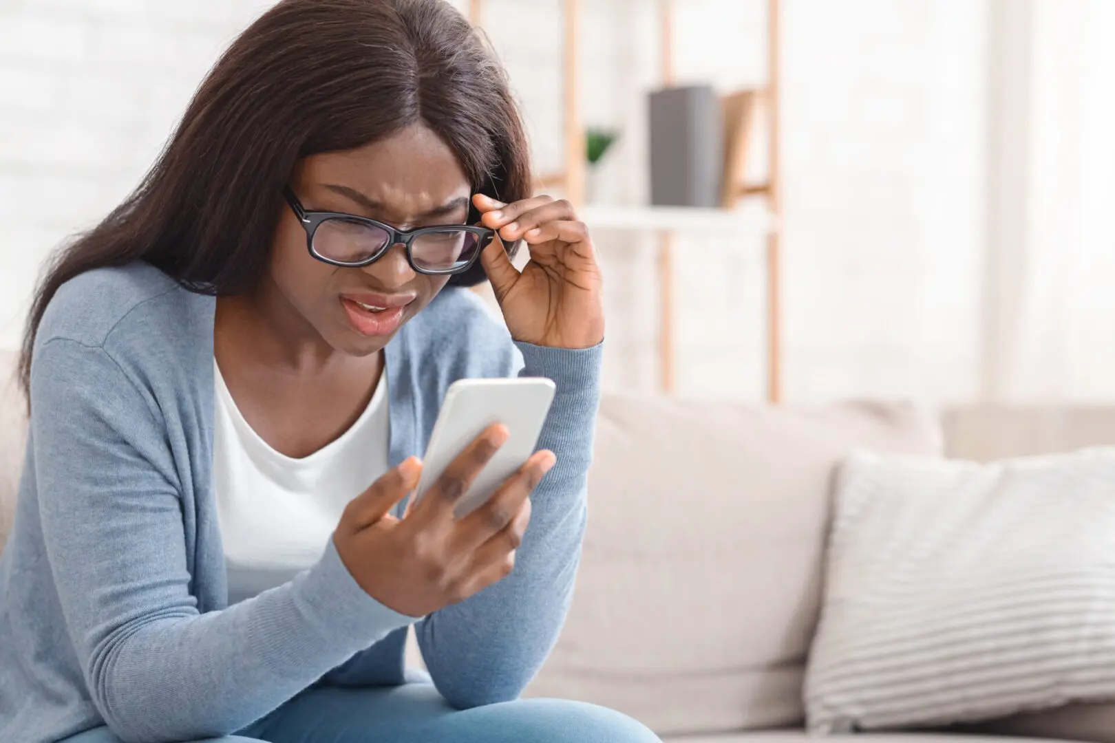 A woman sitting on the couch looking at her phone.