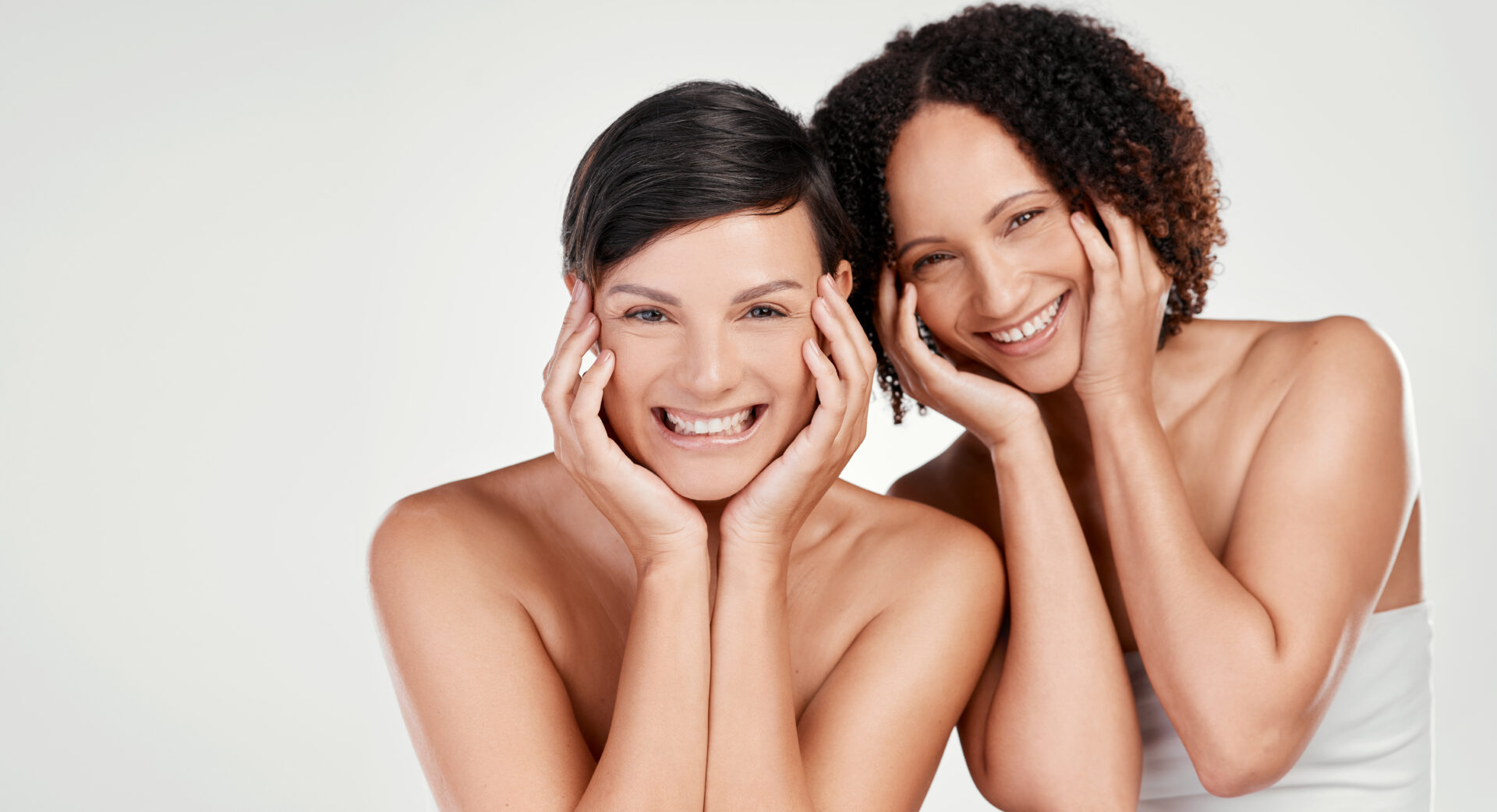 Cropped portrait of two beautiful mature women posing against a grey background in studio.